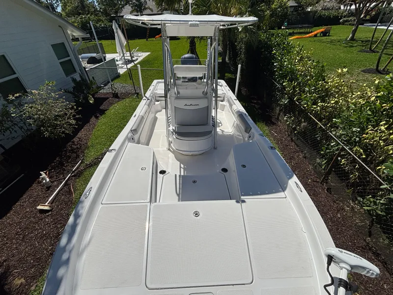 Slide: The Image of 2013 SeaHunter 24 Bay boat docked in a garden setting, showcasing spacious deck and console. - 24