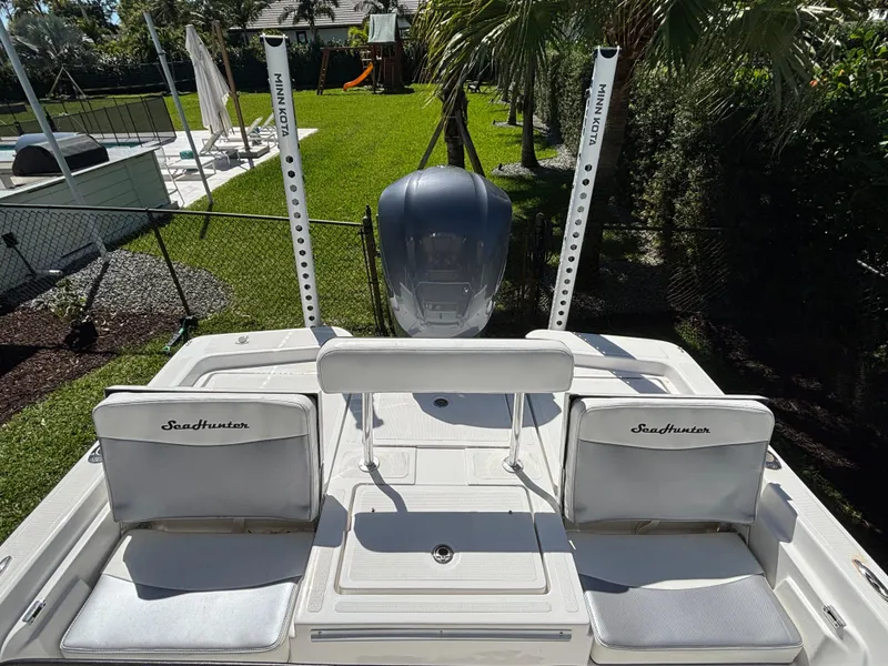 Slide: The Image of 2013 SeaHunter 24 Bay boat with dual seats and motor, in a sunny backyard setting. - 29