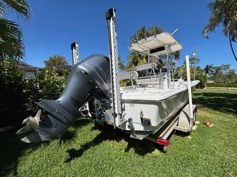 Slide: The Image of 2013 SeaHunter 24 Bay boat with outboard motor on grass, surrounded by palm trees. - 4