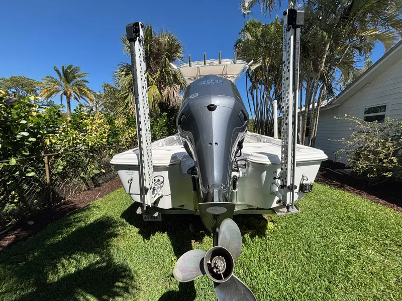 Slide: The Image of 2013 SeaHunter 24 Bay boat with outboard motor, parked on grass, surrounded by tropical plants. - 5
