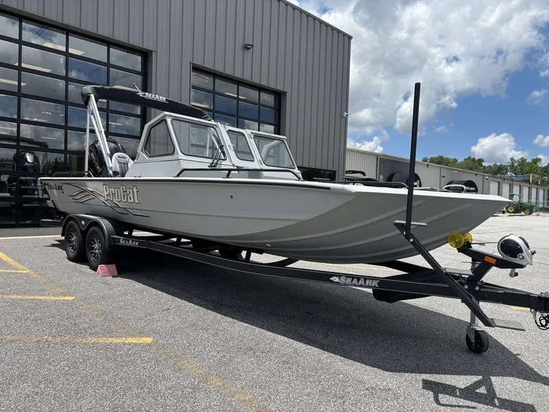 Slide: The Image of 2026 SeaArk ProCat 240 boat on trailer outside a warehouse under a partly cloudy sky. - 10