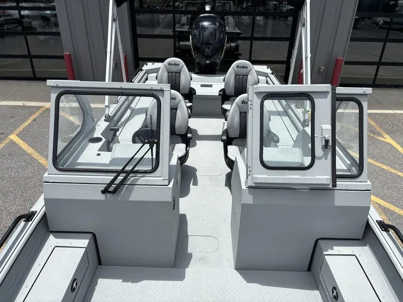 Slide: The Image of 2026 SeaArk ProCat 240 boat interior with seating and windshield, parked outdoors. - 11
