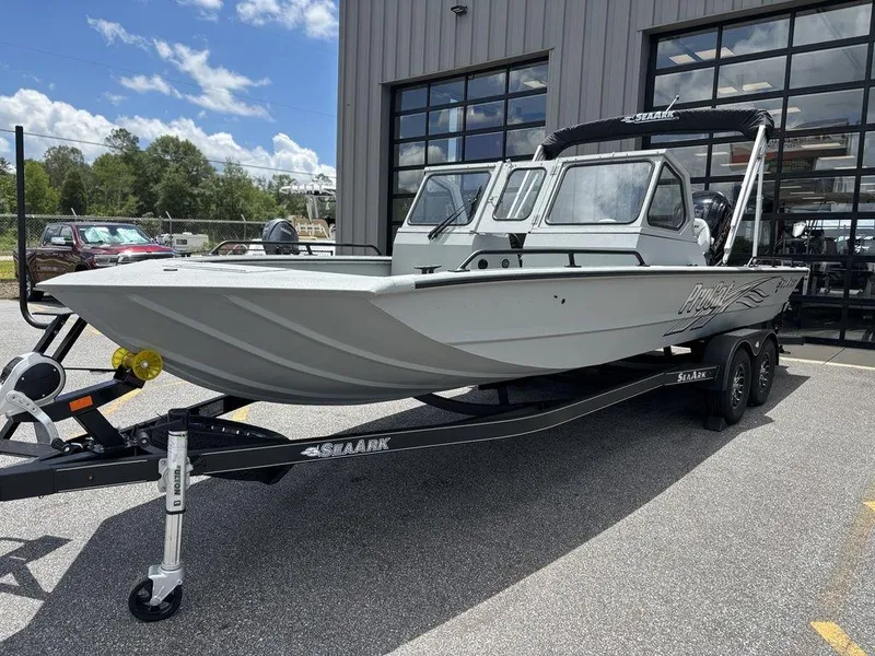Slide: The Image of 2026 SeaArk ProCat 240 boat on trailer, parked outside a building under a cloudy sky. - 5