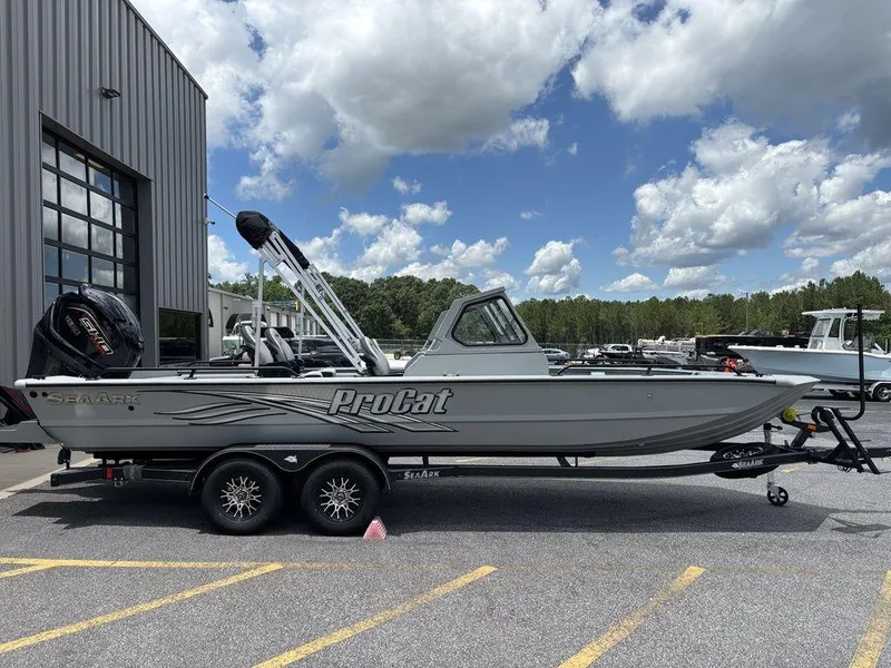 Slide: The Image of 2026 SeaArk ProCat 240 boat on trailer, parked outside a building under a cloudy sky. - 6