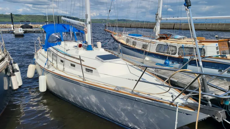 The Image of 1983 Sabre 34 sailboat docked at marina, featuring blue canopy and white hull. - 1