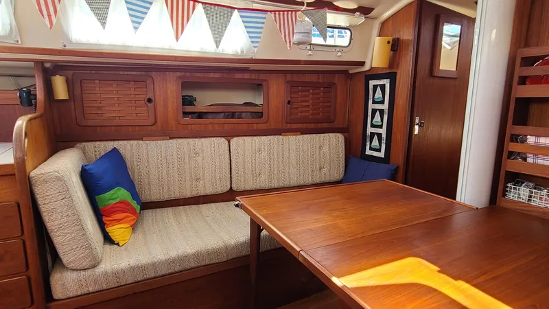 Slide: The Image of Cozy interior of 1983 Sabre 34 sailboat with wooden table and colorful cushions. - 11