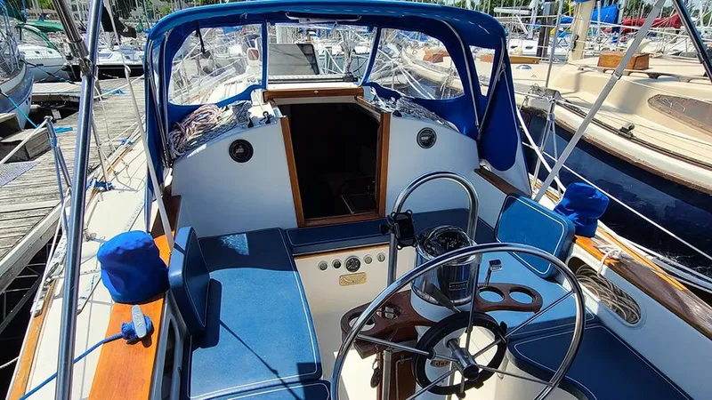 Slide: The Image of 1983 Sabre 34 sailboat cockpit with blue seating and steering wheel, docked at marina. - 17