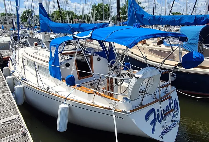 Slide: The Image of 1983 Sabre 34 sailboat docked with blue canvas covers and visible marina background. - 21