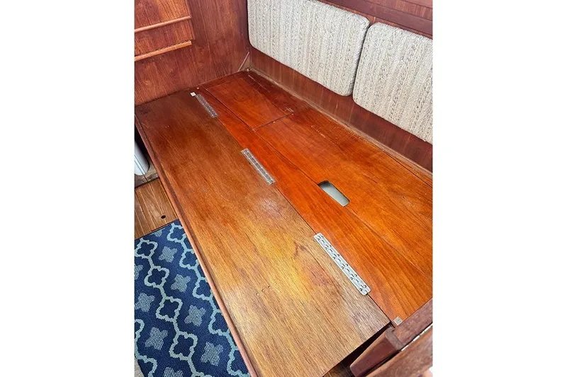 Slide: The Image of 1983 Sabre 34 interior wooden bench with storage compartment and patterned rug. - 24