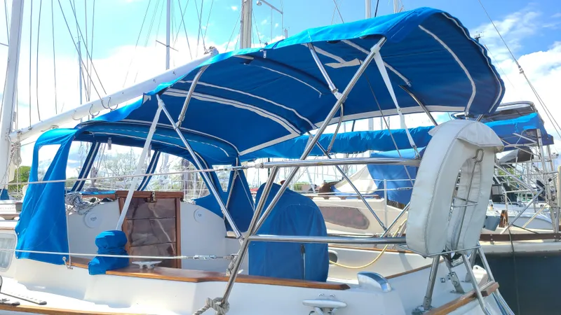 Slide: The Image of 1983 Sabre 34 sailboat with blue canopy and lifebuoy, docked at marina. - 3
