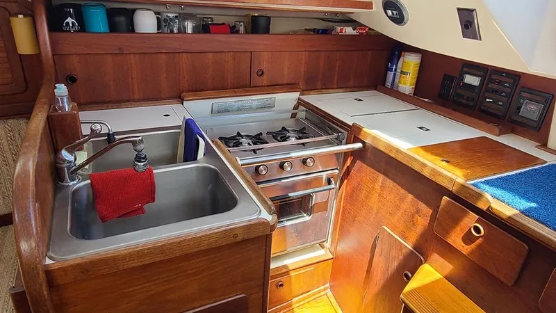 Slide: The Image of 1983 Sabre 34 yacht kitchen with stove, sink, and wooden cabinetry. - 8