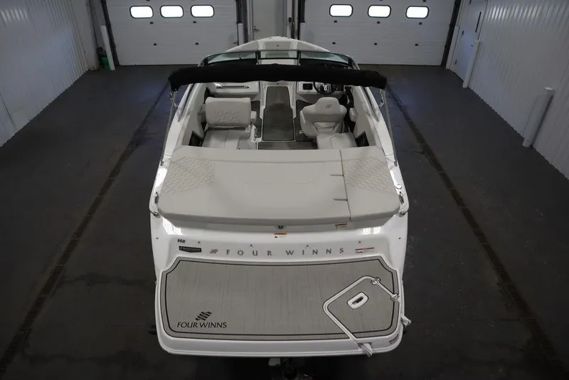 Slide: The Image of 2025 Four Winns H2 Freedom boat in a garage, rear view showcasing seating and deck. - 12