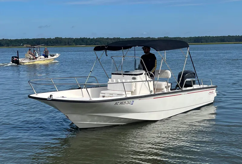 Slide: The Image of 2014 Boston Whaler 210 Montauk boat cruising on a calm lake under a clear sky. - 1