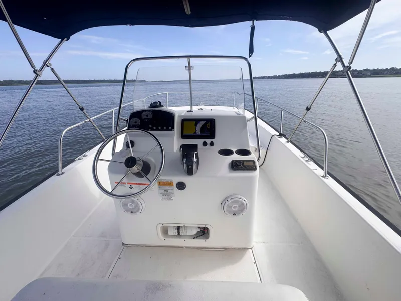 Slide: The Image of 2014 Boston Whaler 210 Montauk boat interior with steering wheel and controls on calm water. - 13