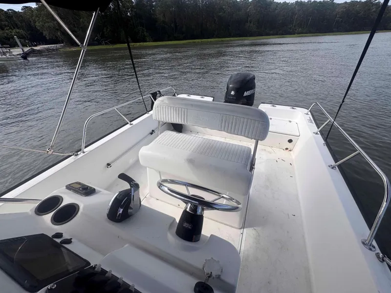 Slide: The Image of 2014 Boston Whaler 210 Montauk boat interior with seating and controls on a calm river. - 15