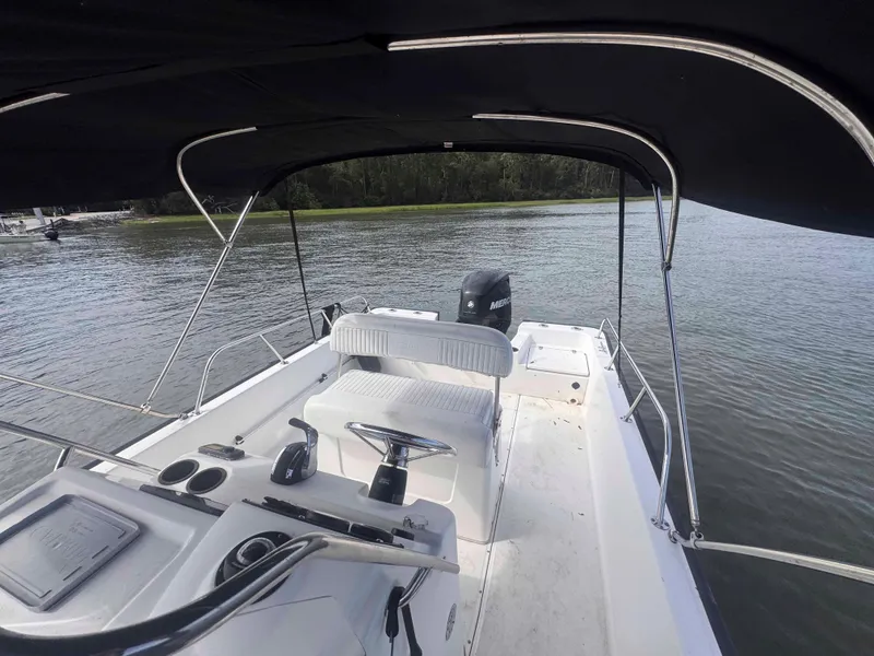 Slide: The Image of 2014 Boston Whaler 210 Montauk boat interior with canopy on calm water. - 16