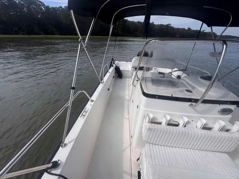 Slide: The Image of 2014 Boston Whaler 210 Montauk boat interior with seating and canopy on calm water. - 17