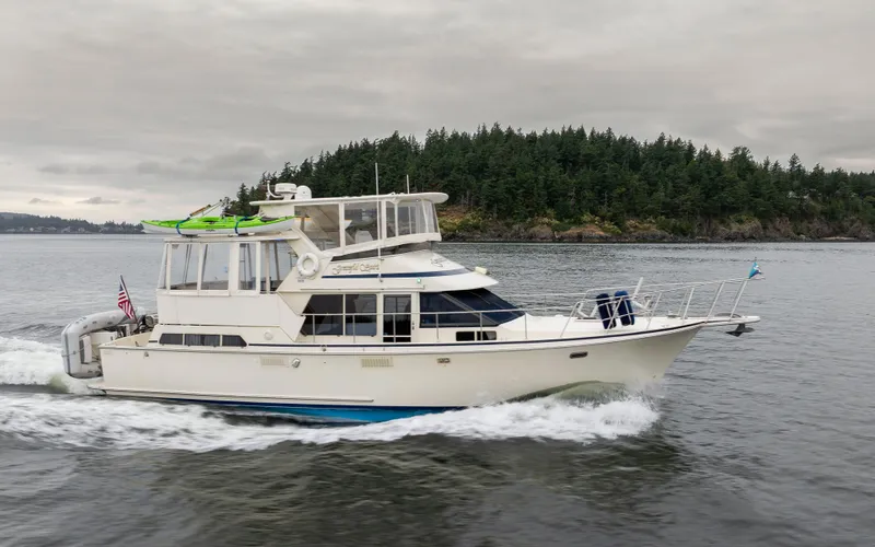 Slide: The Image of 1990 Tollycraft 44 Cockpit Motor Yacht cruising near forested shoreline. - 0