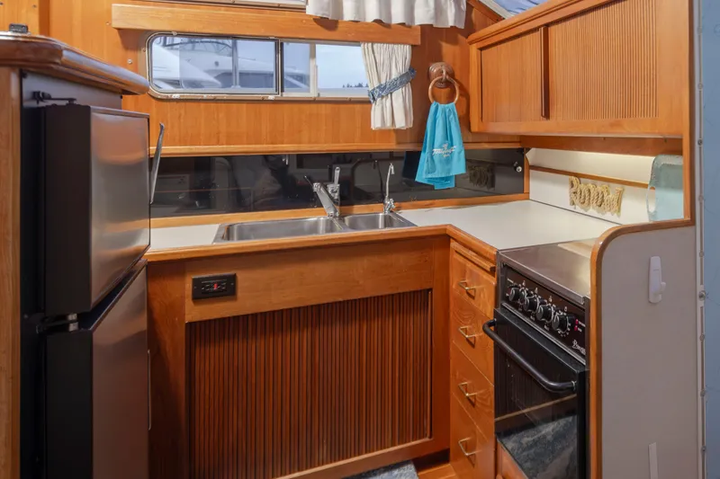 Slide: The Image of 1990 Tollycraft 44 Cockpit Motor Yacht kitchen with wood cabinetry and modern appliances. - 17