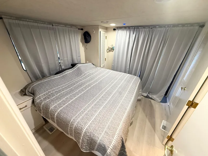 Slide: The Image of Cozy bedroom in 1995 Skipperliner 52 Inter-Coastal Motor Yacht with gray bedding and curtains. - 11
