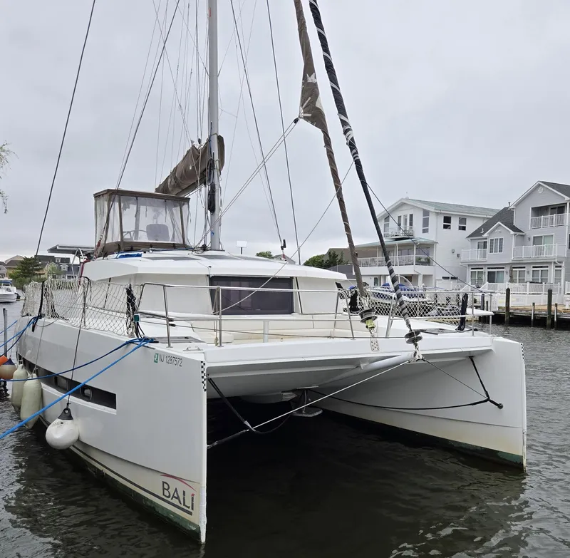 Slide: The Image of 2018 Bali 4.1 Catamaran docked near waterfront homes on a cloudy day. - 32