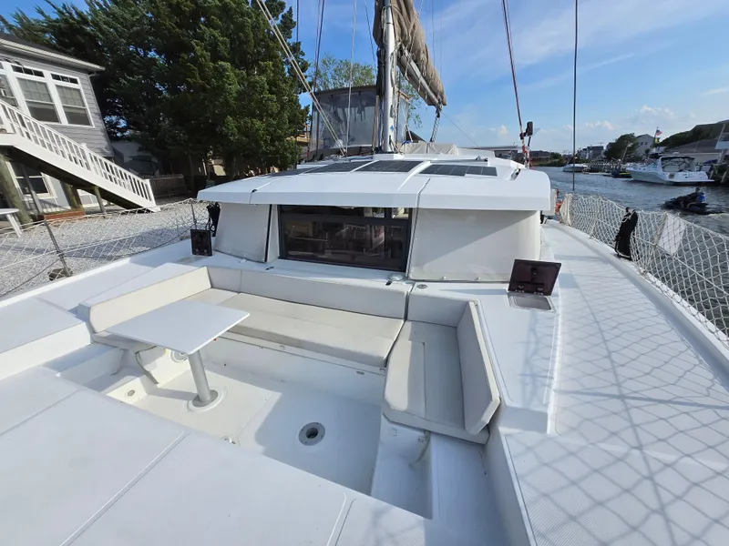 Slide: The Image of 2018 Bali 4.1 Catamaran with spacious deck seating and table, docked by a scenic waterfront. - 4