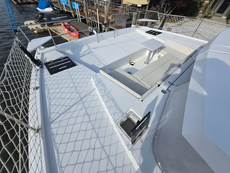 Slide: The Image of 2018 Bali 4.1 Catamaran deck with seating and table, docked by the water. - 8