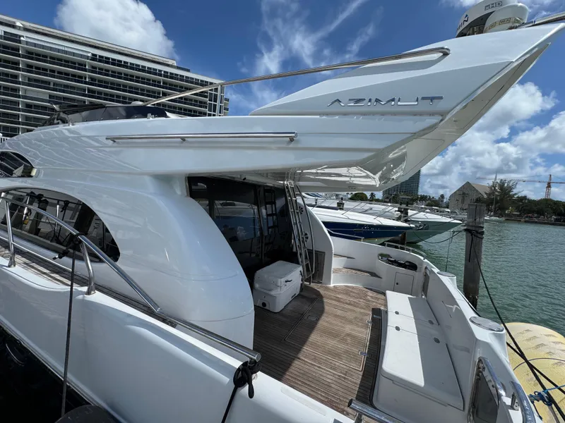 Slide: The Image of 1997 Azimut 54 yacht docked, showcasing sleek design and spacious deck under a clear blue sky. - 22