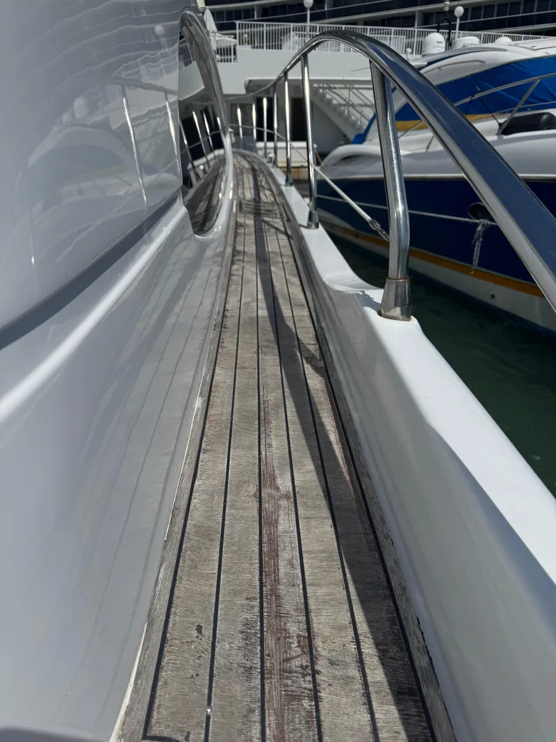 Slide: The Image of 1997 Azimut 54 yacht deck with wooden flooring and metal railings at a marina. - 39
