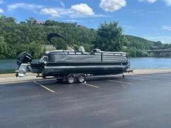 Slide: The Image of 2024 Regency 250 LE3 pontoon boat parked by a scenic river. - 0