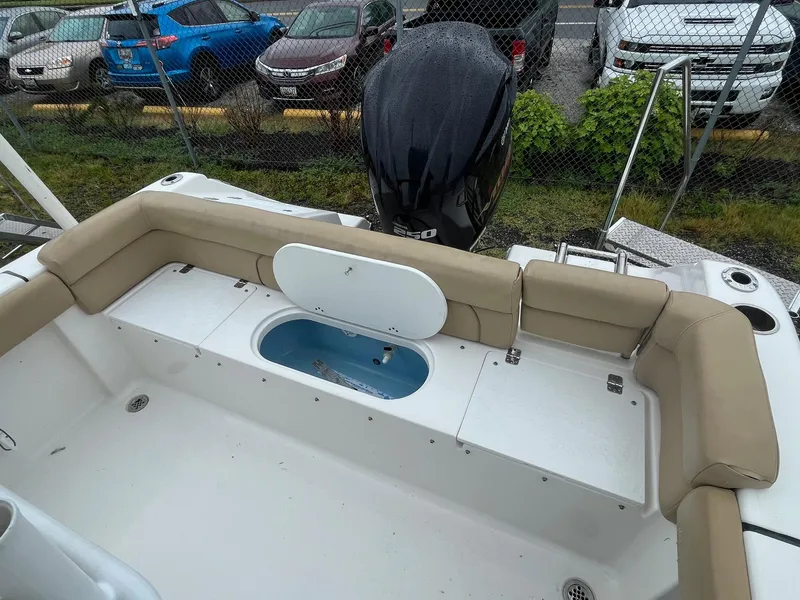 Slide: The Image of 2017 Tidewater 230 LXF boat interior with seating and storage, parked near vehicles. - 12