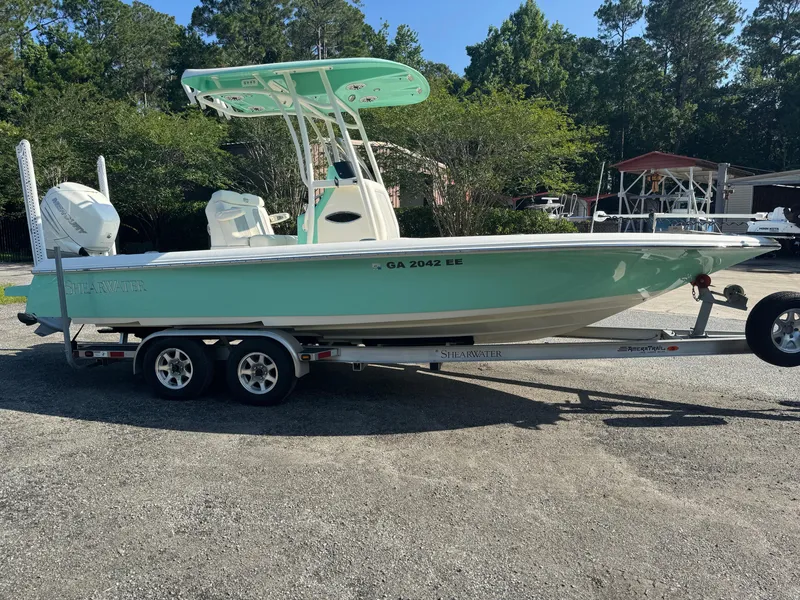Slide: The Image of 2020 ShearWater 250 boat on trailer, mint green hull, parked outdoors. - 4