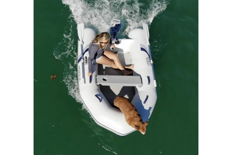 Slide: The Image of 2025 Highfield Roll-Up 230 KAM inflatable boat with person and dog on water. - 2