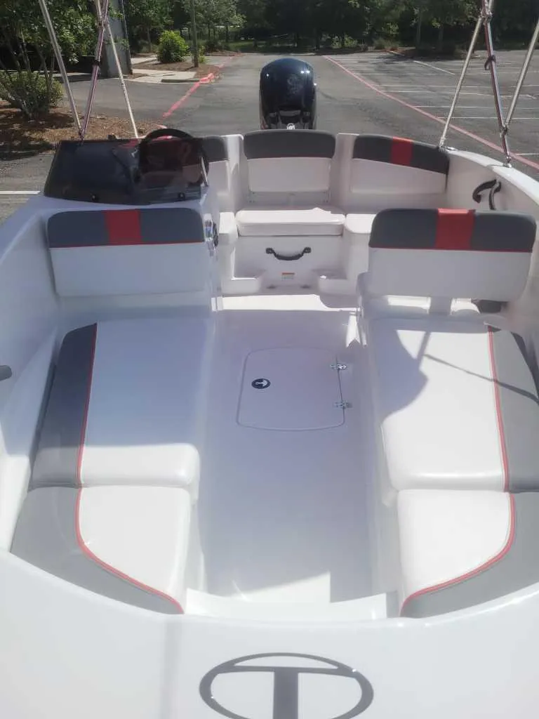 Slide: The Image of 2025 Tahoe T16 boat interior with gray and red seating, parked outdoors. - 4
