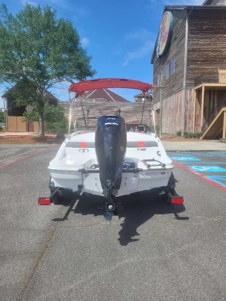Slide: The Image of 2025 Tahoe T16 boat with outboard motor parked near rustic building. - 5