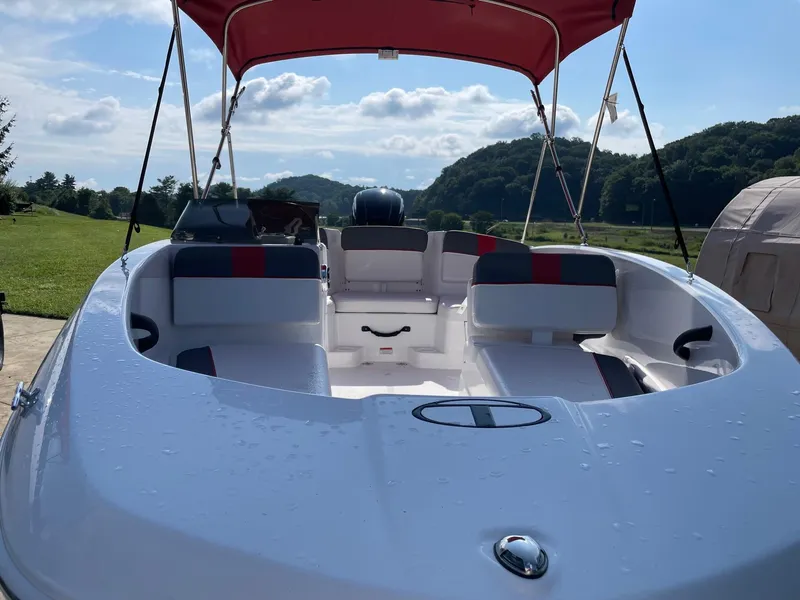 Slide: The Image of 2025 Tahoe T16 boat with red canopy, parked outdoors on a sunny day. - 2