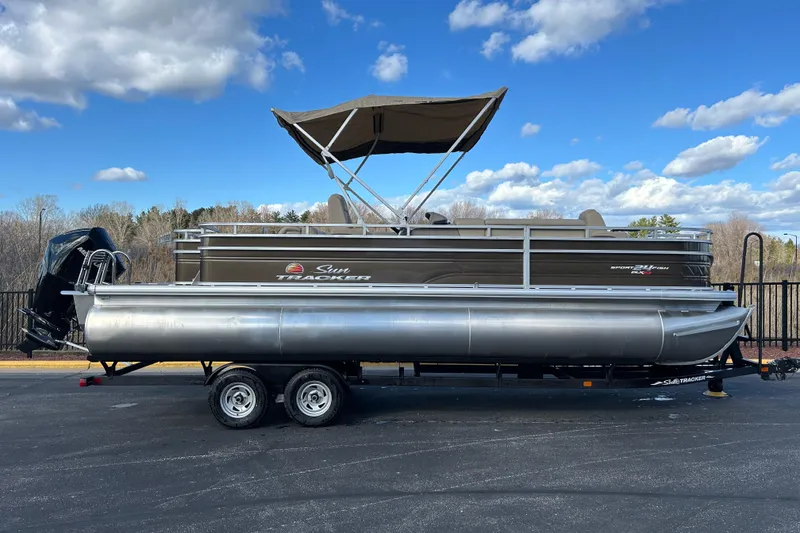 The Image of 2025 Sun Tracker Sportfish 24 XP3 pontoon boat on trailer under blue sky. - 0