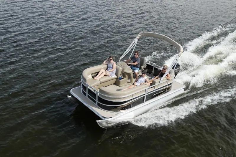 Slide: The Image of 2025 Starcraft LX 16 pontoon boat cruising on a lake with passengers enjoying the ride. - 2