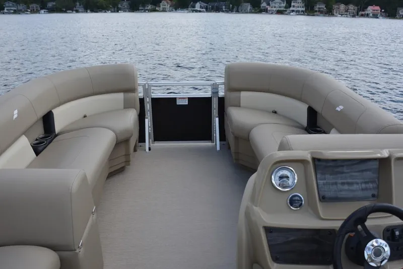 Slide: The Image of 2025 Starcraft LX 16 pontoon boat interior with beige seating on a lake. - 6