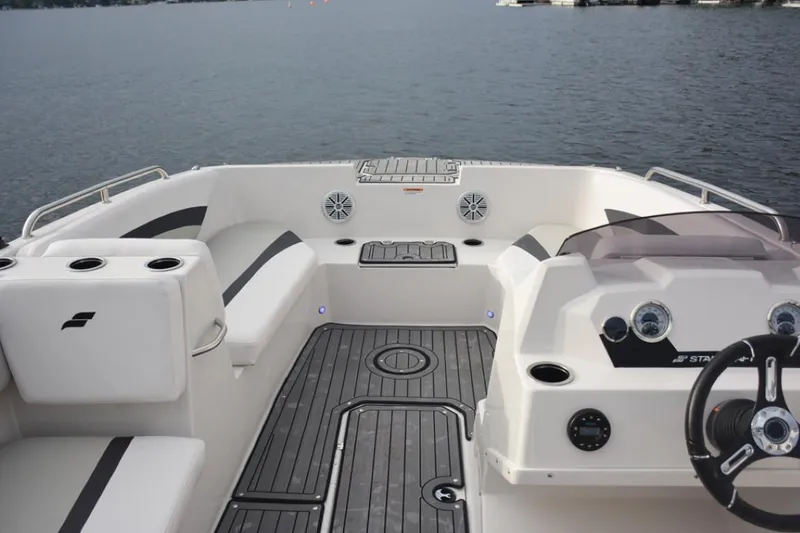 Slide: The Image of 2025 Starcraft SVX 171 boat interior with seating and steering wheel on a calm lake. - 12