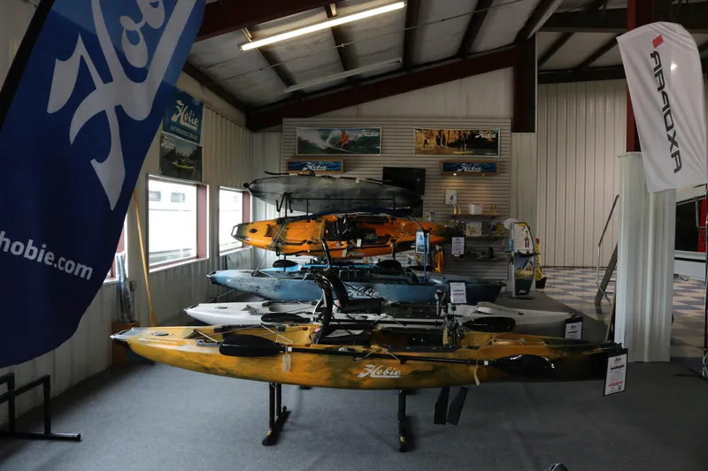 Slide: The Image of 2024 Hobie Mirage Outback kayaks displayed in a showroom with promotional banners. - 3