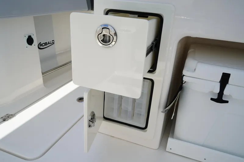 Slide: The Image of 2025 Robalo R300 Center Console storage compartment with open door and latch. - 17