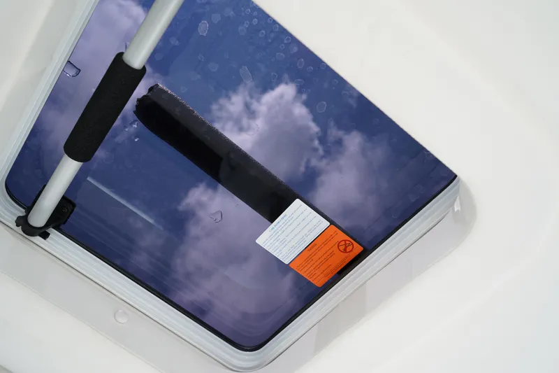 Slide: The Image of 2025 Robalo R300 Center Console hatch with sky reflection and safety sticker. - 24