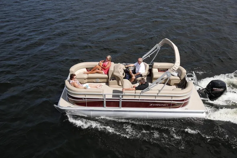 Slide: The Image of 2025 Starcraft 20 LX pontoon boat cruising on water with passengers relaxing. - 1