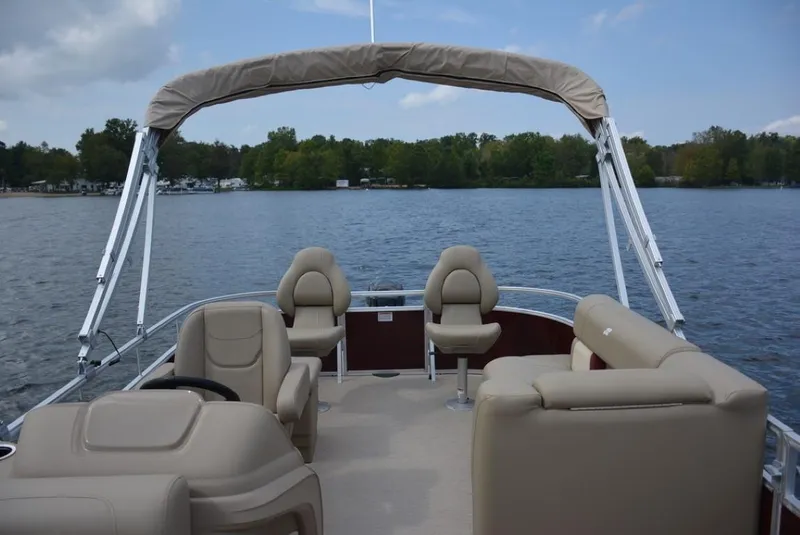 Slide: The Image of 2025 Starcraft 20 LX pontoon boat on a serene lake with beige seating. - 11