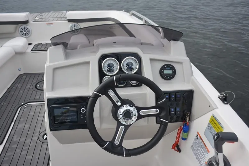 Slide: The Image of 2023 Starcraft 211 SVX boat dashboard with steering wheel and control panel on water. - 13