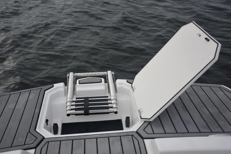 Slide: The Image of 2023 Starcraft 211 SVX boat with open storage compartment and ladder on water. - 17