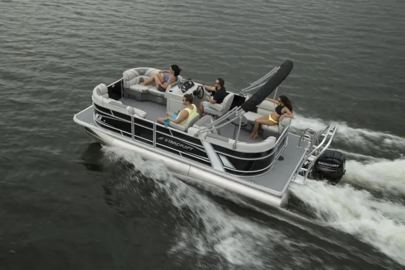 Slide: The Image of 2025 Starcraft EX 24 pontoon boat cruising with passengers on a lake. - 2