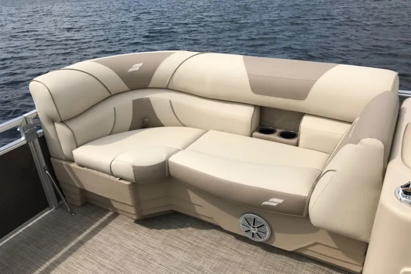 Slide: The Image of 2025 Starcraft EX 24 pontoon boat with beige seating on a lake. - 5