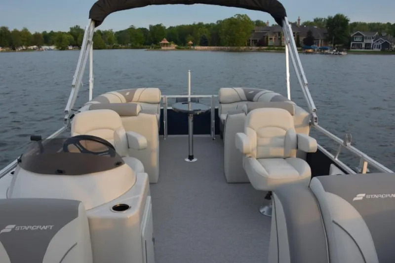 Slide: The Image of 2025 Starcraft EX 24 pontoon boat on a lake, featuring spacious seating and modern design. - 6